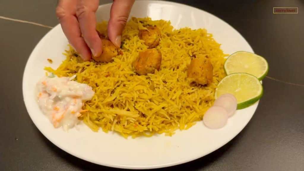 fish kofta served on a plate with some raita, sliced onions and lemon wedges
