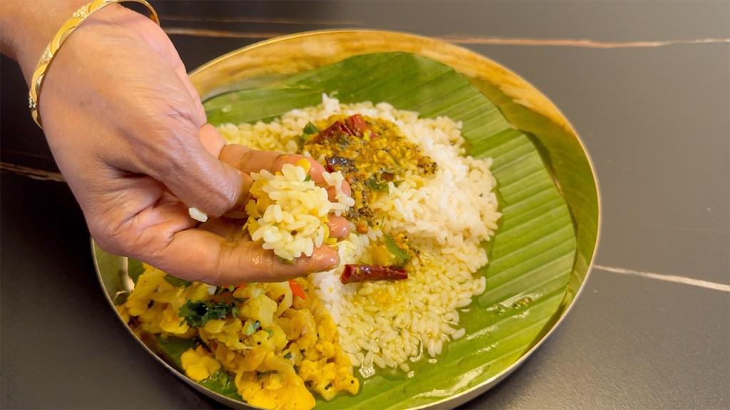 a plate of rice with a generously poured rasam and a cauliflower fry at the side