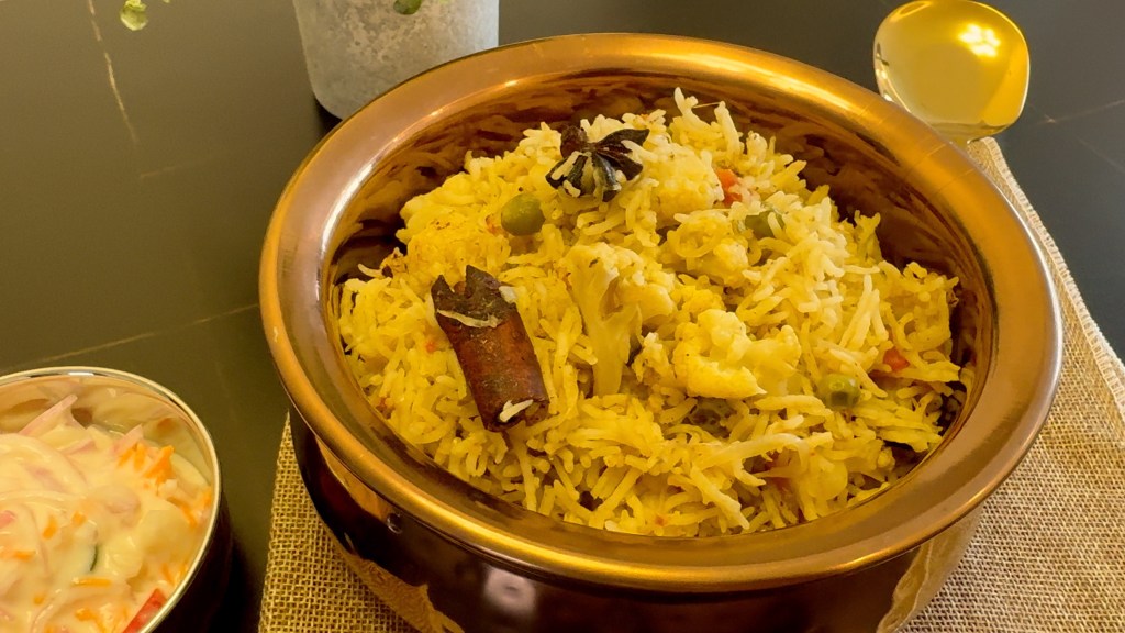gobi matar pulao in a serving bowl along with raita 