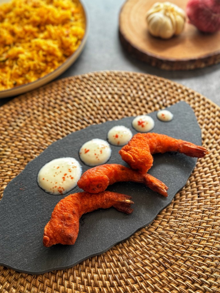 prawn pakora in a serving plate with raita and biryani at the side