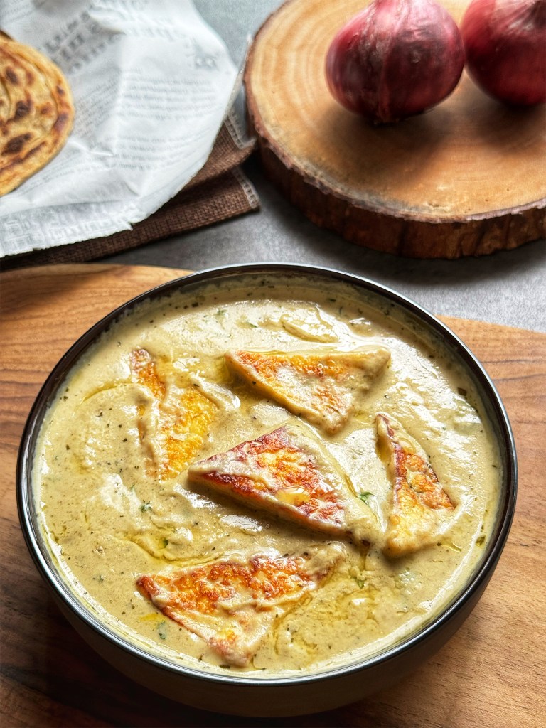 nawabi paneer in a serving bowl with paratha at the side