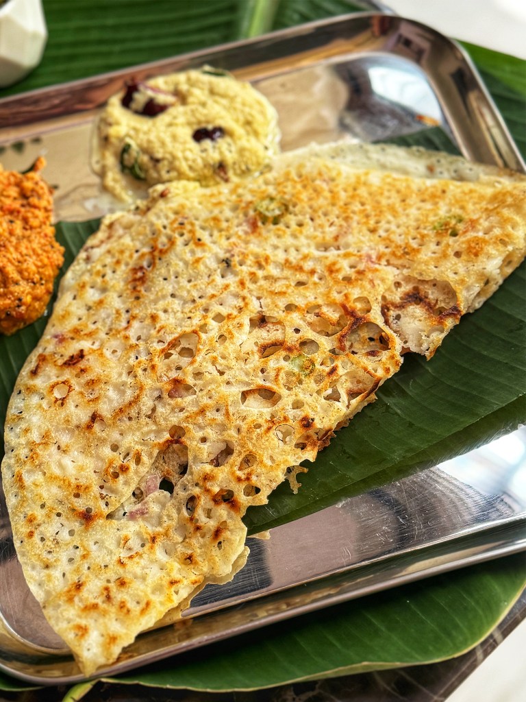 rava dosa in a serving plate with chutneys at the side